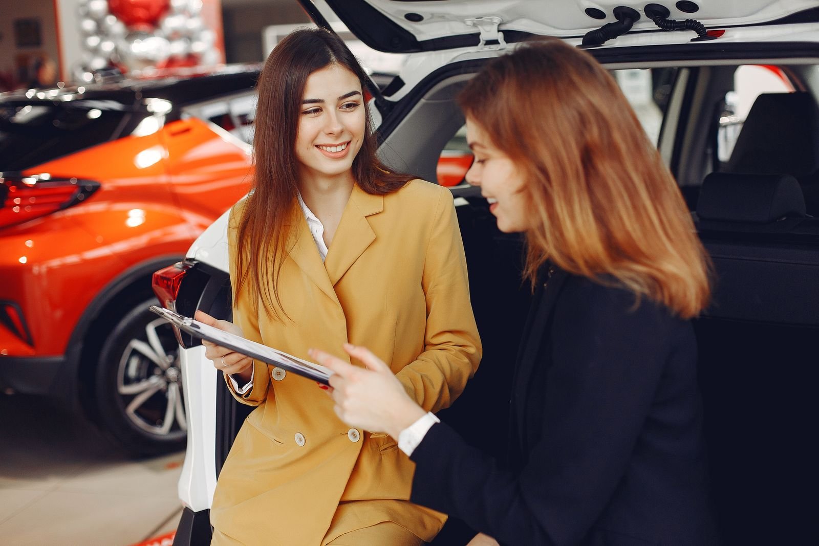Dealership advisor helping a customer beside a new vehicle
