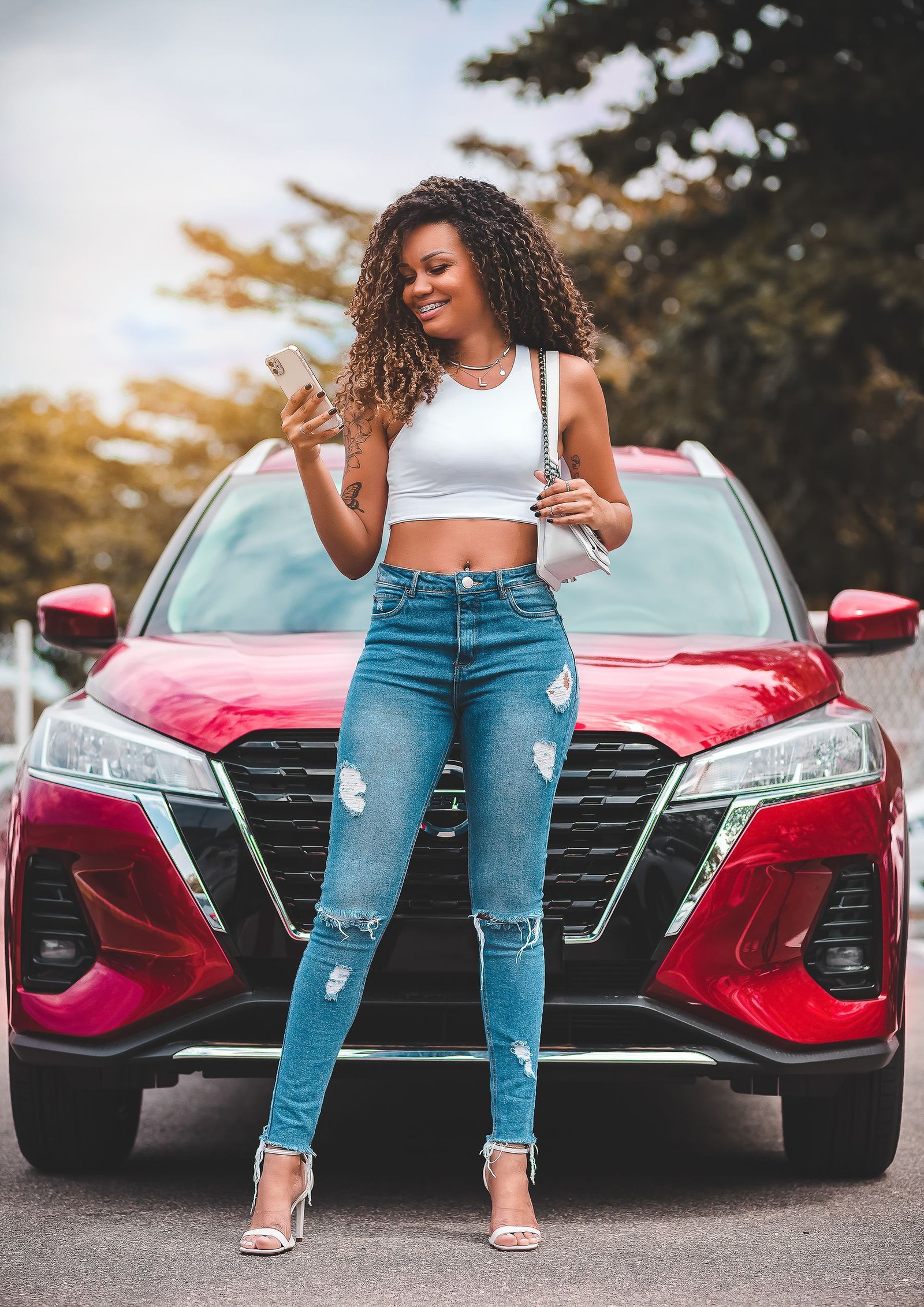Vehicle owner using her phone beside a red car